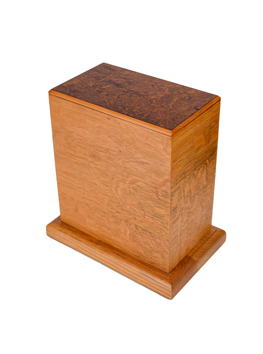 Handcrafted cremation urn featuring quarter sawn Oak tower with medullary ray figures, solid Oak base, and highly figured English Walnut Burl top from 1885, 200 cubic inch capacity, angled view