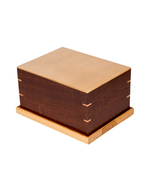 Handcrafted cremation urn made from 1920s Black Walnut body with inlaid English Walnut Burl from an 1885 piano, Sitka Spruce top from antique soundboard, 54 cubic inch capacity, angled view, satin finish