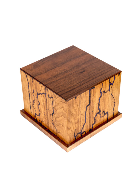 Angled view of 250 cubic inch oak urn with Lichtenberg burns and blue epoxy, handcrafted from 1890 American piano wood with walnut top