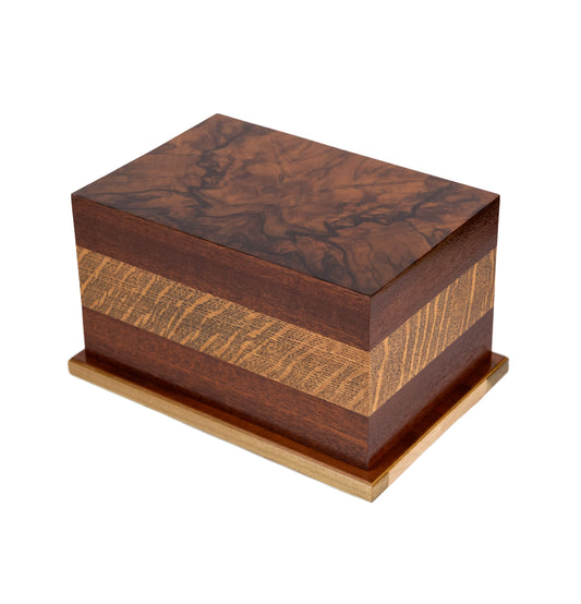 Handcrafted cremation urn featuring quarter sawn Oak band from 1923 English piano, figured American Black Walnut body, and highly figured English Walnut Burl top from 1890 piano, 210 cubic inch capacity, angled view