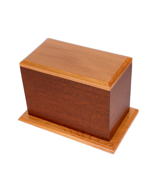 Handcrafted cremation urn with warm-stained Sapele wood body and natural American White Ash top and base, 160 cubic inch capacity, angled view